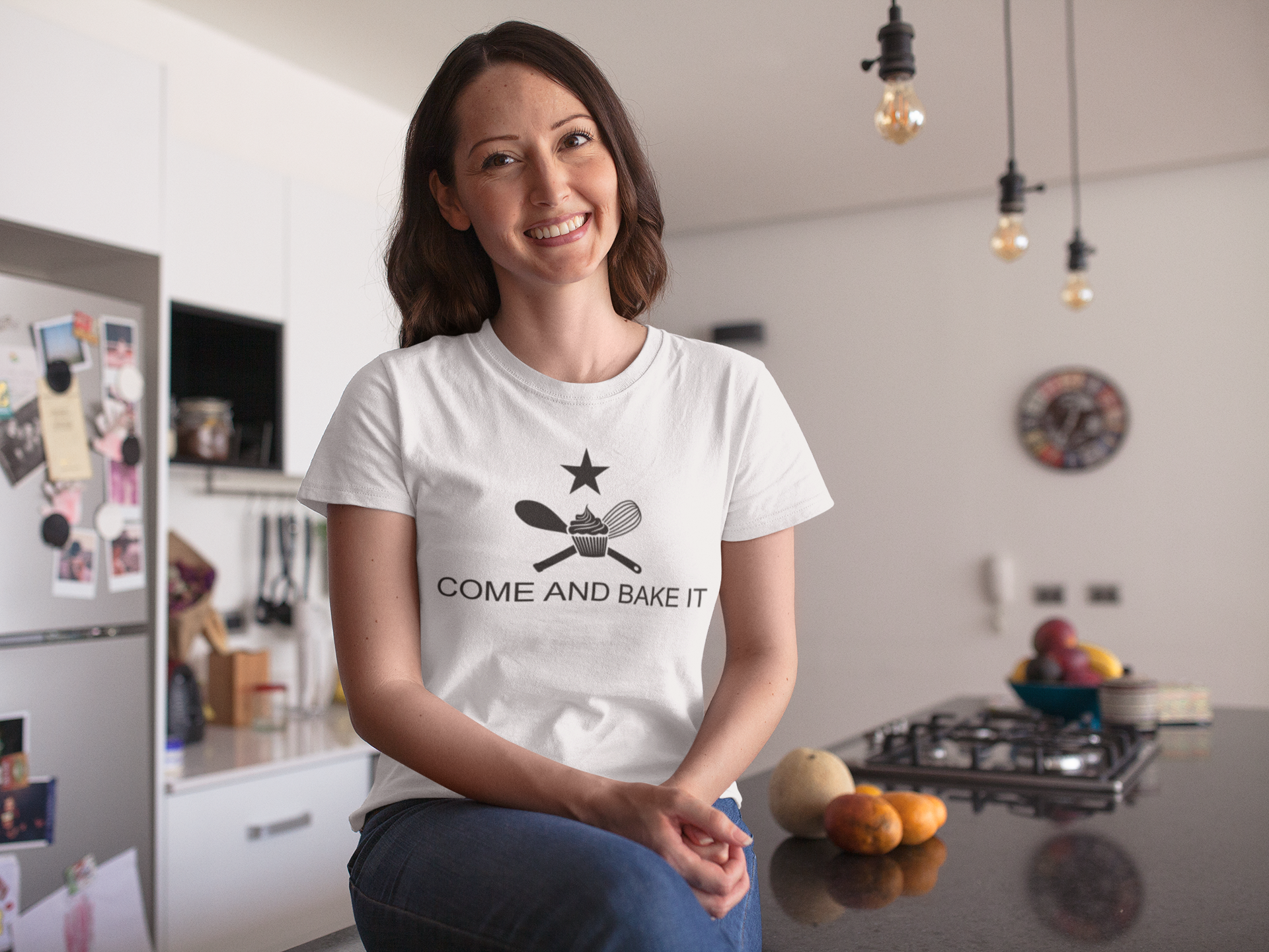 woman wearing white shirt with text "come and bake it" with a cupcake, whisk, and mixing spoon